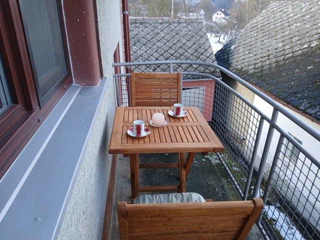 Balkon apartmánu se stolkem, dvěma židlemi a kávovým servisem.